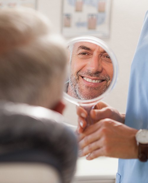 A dentist showing their patient his new smile in the mirror