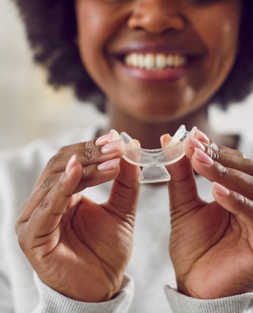 a woman holding pre-filled whitening trays